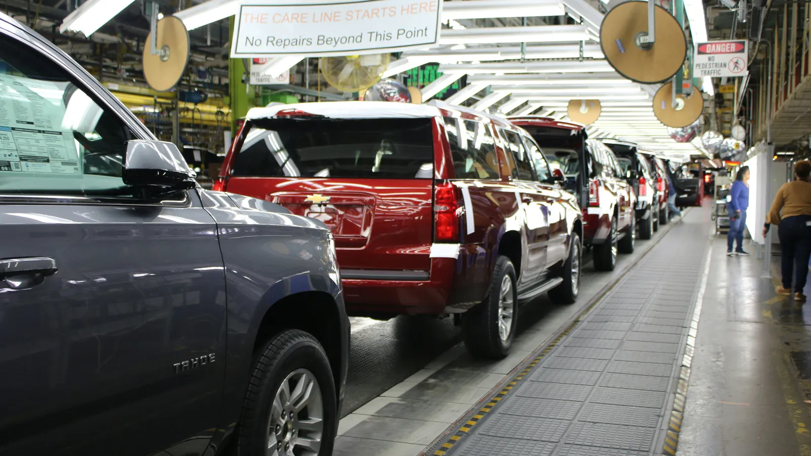 Vehicles moving along a car factory assembly line inside a large manufacturing plant